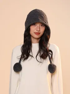 Warm wool elf pumpkin cloak knit hat with pom-poms worn by a model in soft lighting