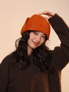 Close-up of woman wearing a warm orange 100% wool knitted aviator hat with ear flaps