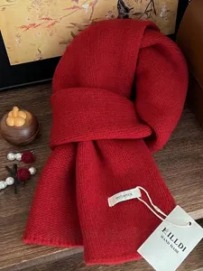 Detailansicht eines weichen roten Schals aus 100% Wolle mit feiner Strickstruktur und Tag.