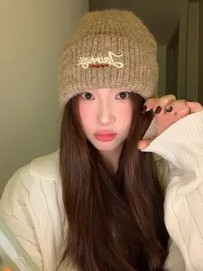 Detail einer braunen Strickmütze mit Journey-Stickerei auf asiatischem Model