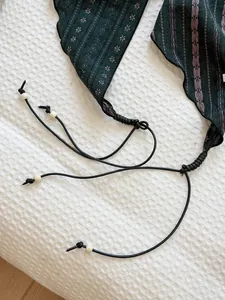 Close-up detail of a vintage dark green triangle scarf with beads and string