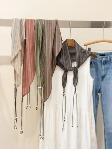 Close-up of retro patterned triangle scarves in earthy tones featuring beaded tassels