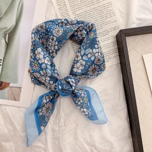 Close-up of a blue floral cotton-linen scarf tied in a stylish retro knot detail view