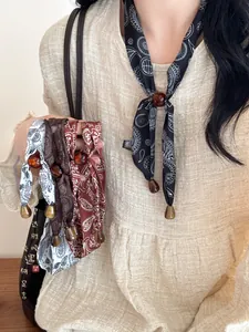 Detailansicht von Retro-Paisley-Halstuchketten mit Perlen auf einem Leinenkleid