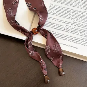 Nahaufnahme einer Vintage-Halskette aus Seide mit Paisleymuster und Bernsteinperle