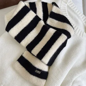 Detailed view of the black and white striped knitted crossover scarf showing cozy texture