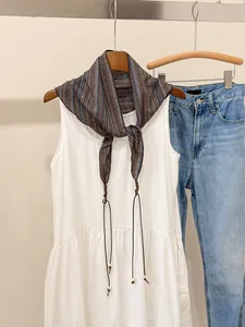 Close-up of retro striped triangular scarf tied over a white dress for styling