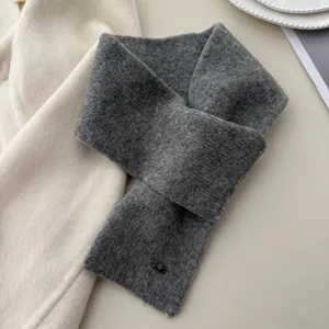 Detail of a premium gray knit cross-over scarf showing its soft texture and cozy design