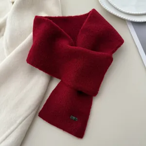 Detailed macro view of dark red knitted cross-over neck warmer scarf showing soft wool texture
