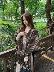 Detailweergave van een bruine geruite dames sjaal poncho met franjes buiten