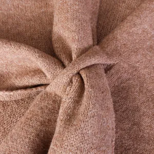Close-up detail of soft wool blend knit fabric featuring a stylish twisted knot design.