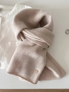Detailed view of soft beige textured 100% wool fine knit scarf with small gold charm