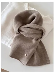 Close-up of soft taupe 100% wool fine knit vintage scarf with circular metal tag
