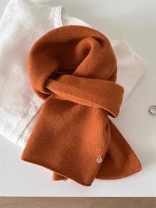 Close-up of soft burnt orange 100% wool fine knit scarf with small metal tag