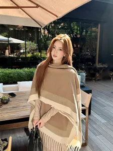 Elegante gebreide poncho met kleurvlakken en franjes in een buitenomgeving