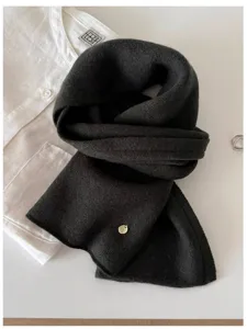 Close-up detail of soft 100% wool fine knit scarf in charcoal black with gold metal tag
