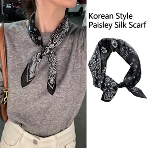 Close-up detail of a vintage black paisley silk scarf tied as an elegant neck accessory