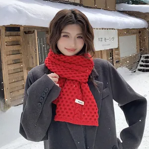 Detalle de una bufanda de punto rojo grueso usada por una modelo en un paisaje invernal