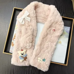 Close-up detail of a soft pink faux fur scarf featuring a cute bear patch and lace bow