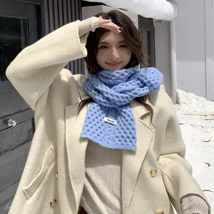 Detalle del tejido de ochos grueso de una cálida bufanda azul de invierno en una modelo