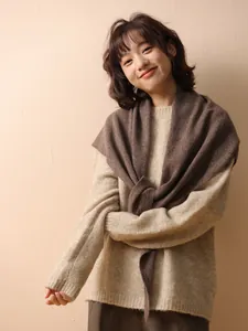 Detail view of brown Australian wool knitted triangle shawl worn over a beige sweater