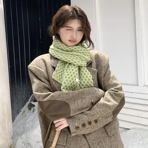 Bufanda de punto verde claro con textura gruesa mostrada por modelo en entorno nevado
