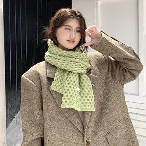 Primer plano de una bufanda de invierno verde con tejido de gofre usada por una modelo