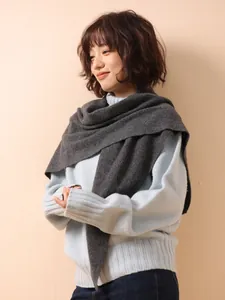 Detail of a dark gray 100% wool knitted triangle shawl worn over a light blue sweater.