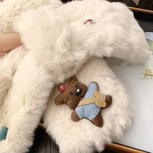 Detailed view of a soft white plush faux fur scarf featuring a cute brown teddy bear accessory