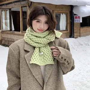 Detalle de una bufanda de punto verde gruesa con textura de gofre en una escena de nieve