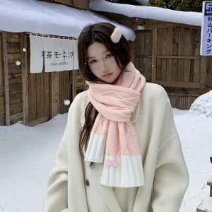Close-up of soft pink and white cable knit scarf worn by model in a snowy winter setting