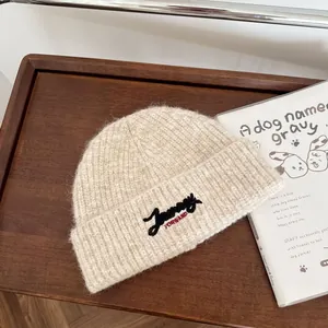 Detailansicht des schicken gestickten Logos auf dieser beigefarbenen Wintermütze.