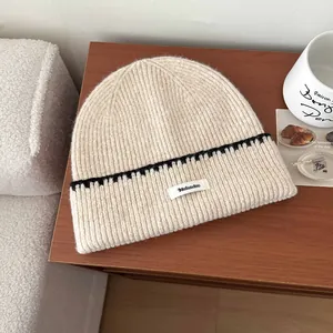 Primo piano di un berretto in maglia a coste beige con striscia nera ed etichetta