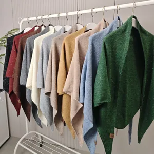Detailweergave van veelkleurige gebreide wollen sjaals met lovertjes op een rek.