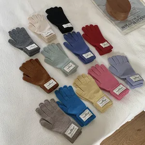 A diverse collection of multi-color knitted winter warm gloves shown on a white textured surface