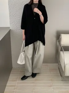 Dettaglio di un elegante scialle in maglia nero con pantaloni larghi grigi in studio.