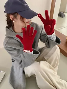 Red 100% merino wool knit gloves worn by a model in a cozy winter lifestyle setting