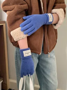A close-up detail of blue knitted winter gloves worn with a stylish brown fleece jacket