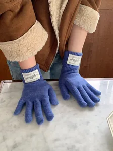 Detailed view of warm blue knitted winter gloves featuring a stylish white brand label