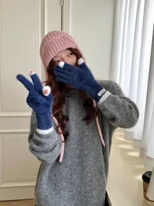 Soft navy blue coral fleece gloves worn by a model in a cozy winter interior setting