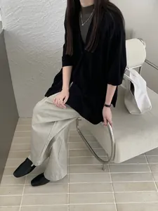 Elegante scialle in maglia nera indossato con pantaloni larghi grigi in camera