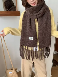 Close-up of a brown wool blend scarf with fringe tassels and white brand label