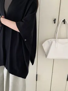 Dettaglio ravvicinato di scialle in maglia nera con bottone laterale e spacco da donna