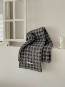 Macro detail view of a cozy gray checkered knitted scarf draped on a white ledge