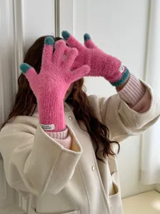 Close-up of soft raspberry pink coral fleece gloves with touch screen teal fingertips.