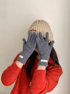 Close-up of a woman wearing grey 100% merino wool knitted gloves with white wool labels