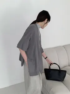 Modella che indossa un cardigan in maglia grigia in stile cinese con borsa nera