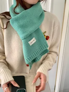 Detail van een gezellige mintgroene gebreide sjaal met minimalistisch ARCLSEE-label.