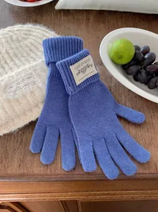Close-up of blue knitted winter warm gloves with a decorative brand woven label detail
