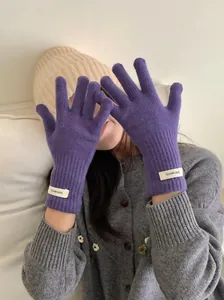 Detail view of 100% wool purple knitted gloves on hands for winter warmth